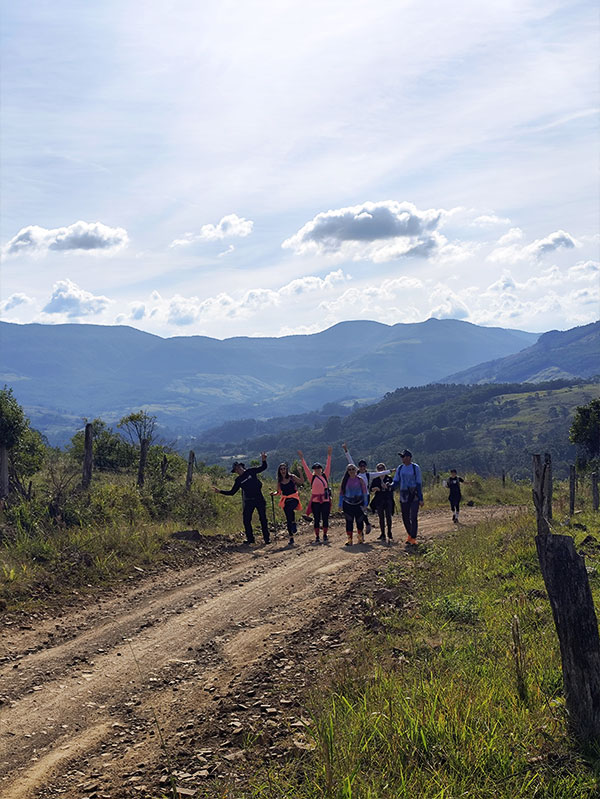 Grupo realizando trilha em estrada rural de Caraá RS com vista para as montanhas do Litoral Norte do Rio Grande do Sul