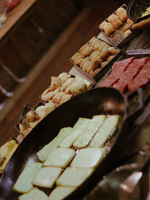 Mesa com café colonial no Lar do Campo, em Caraá/RS, com pães, bolos, salgados, queijos e outras delícias servidas em um ambiente rural acolhedor.