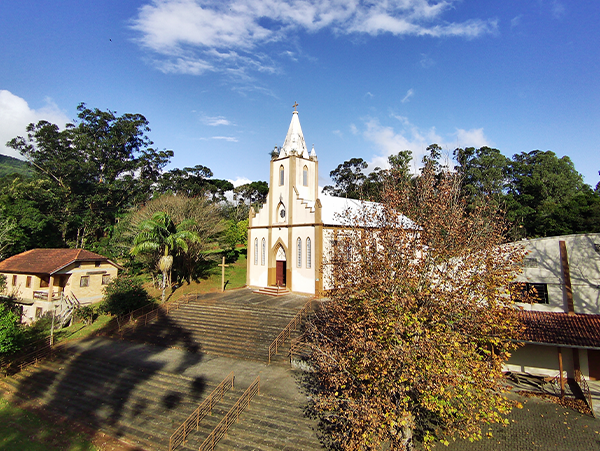 Igreja de arquitetura colonial com escadaria de pedra e vegetação nativa no entorno em Caraá