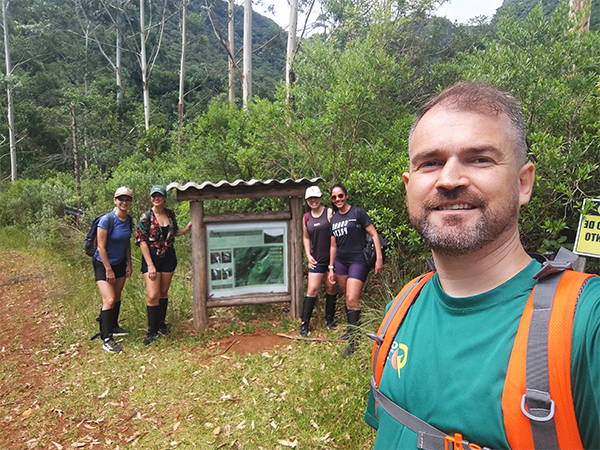 Queda d'água alta e estreita descendo por um paredão de pedra escura cercado por mata atlântica densa